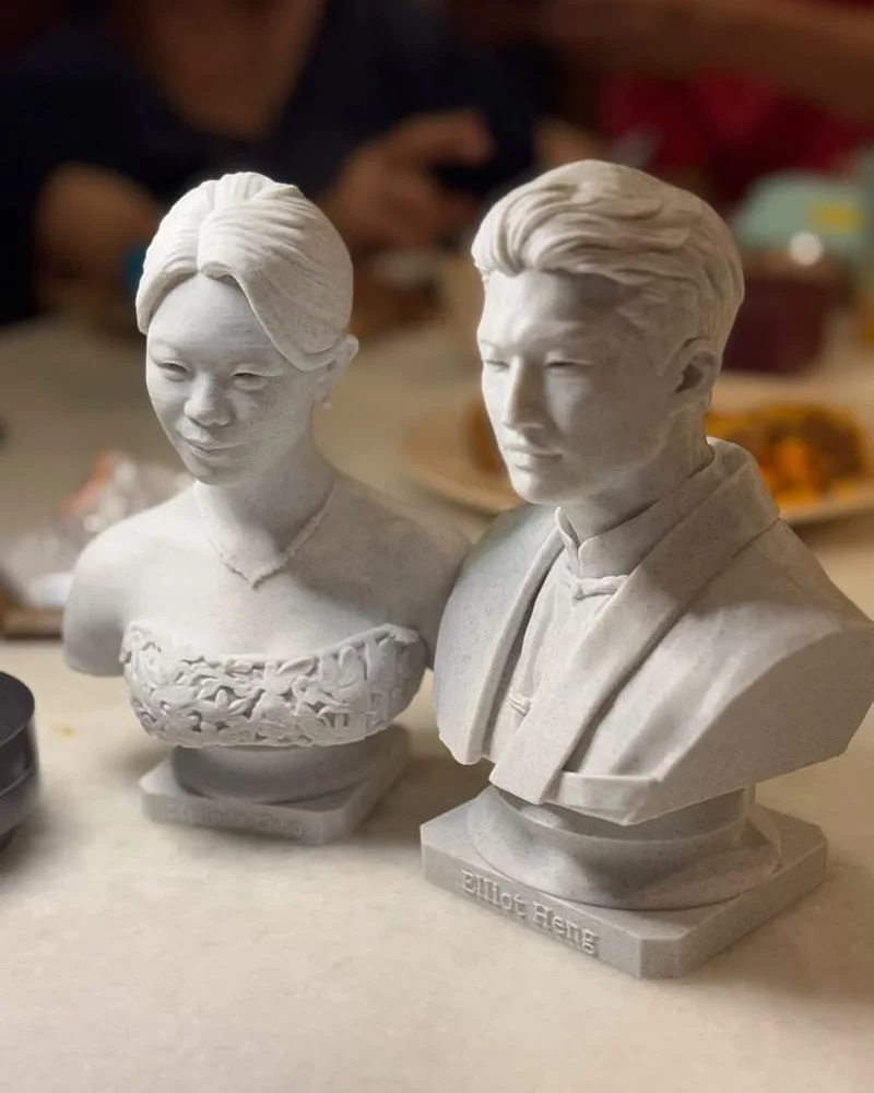 Two marble-effect PLA statue caricatures with names on their bases